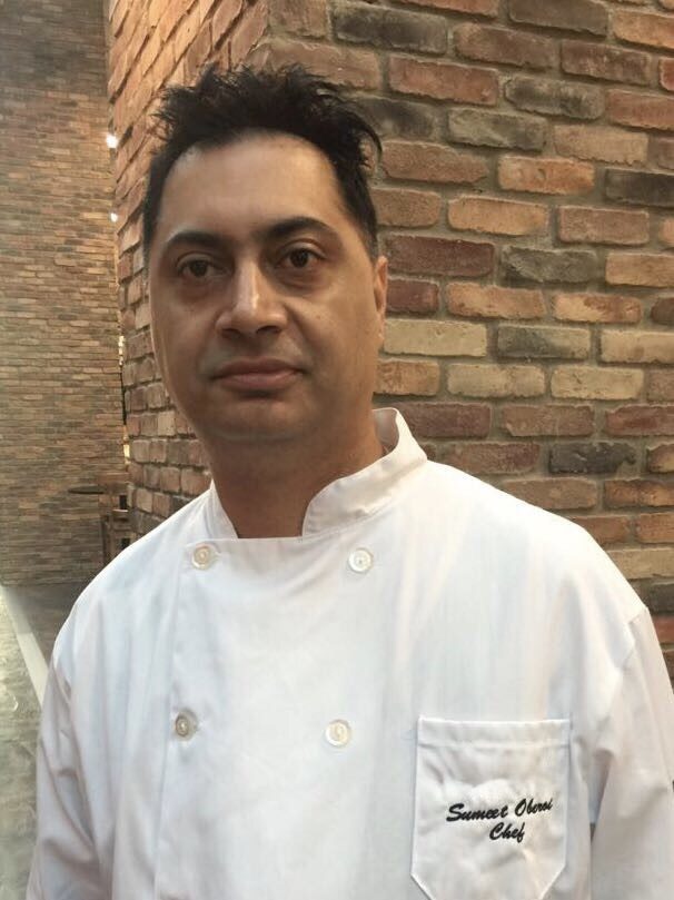 Chef in white uniform against brick wall